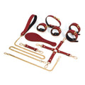 Burgundy red eight-piece leather bondage accessory set with gold-tone hardware