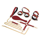 Burgundy red eight-piece leather bondage accessory set with gold-tone hardware
